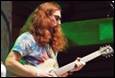 A person with long red hair playing a guitar

Description automatically generated