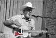 A person in a cowboy hat playing guitar

Description automatically generated