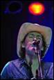 A person wearing a cowboy hat singing into a microphone

Description automatically generated